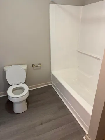 a white toilet sitting next to a bath tub
