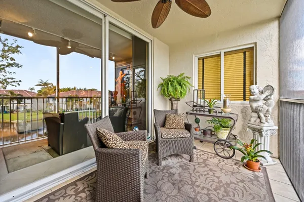 a living room with patio furniture and floor to ceiling windows