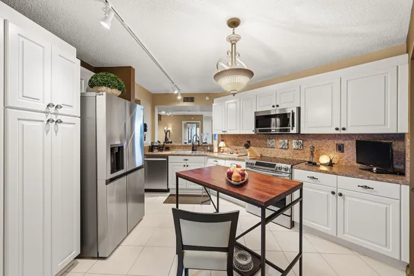 a kitchen with stainless steel appliances granite countertop a refrigerator a sink dishwasher a stove a microwave oven a refrigerator with island and chairs