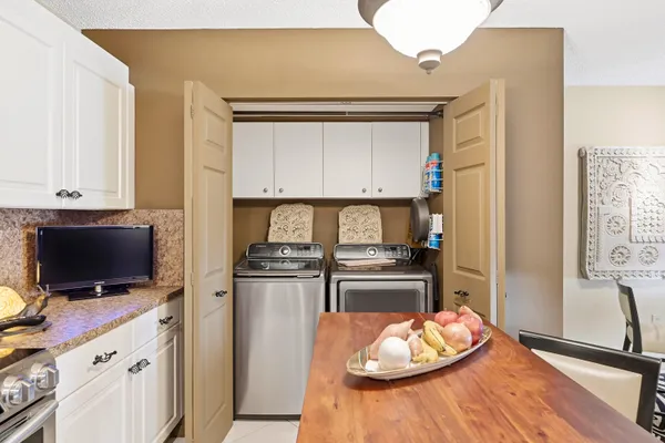 a living room with stainless steel appliances furniture a flat screen tv and a window