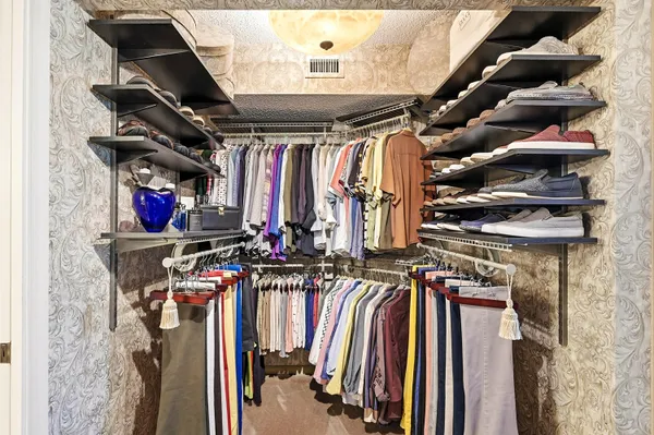 a view of walk in closet with clothes and shoes