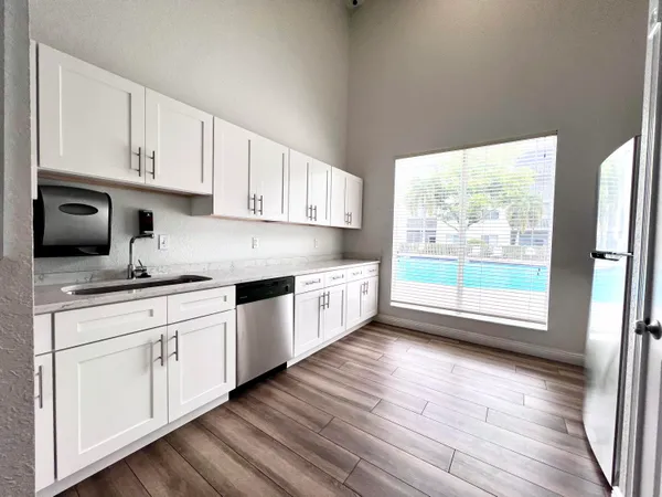 a kitchen with stainless steel appliances granite countertop a stove a sink and white cabinets with wooden floor next to windows