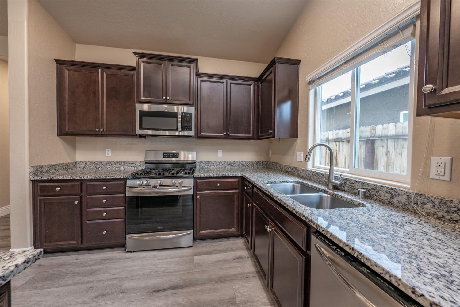 742 Strada Street Lemoore, CA 93245 - Photo 11 of 40 a kitchen with granite countertop cabinets stainless steel appliances and a sink