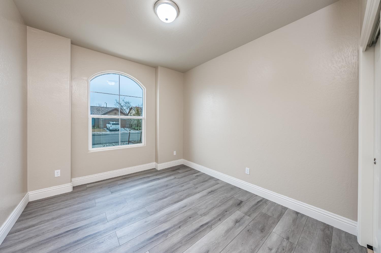 742 Strada Street Lemoore, CA 93245 - Photo 16 of 40 an empty room with wooden floor and windows