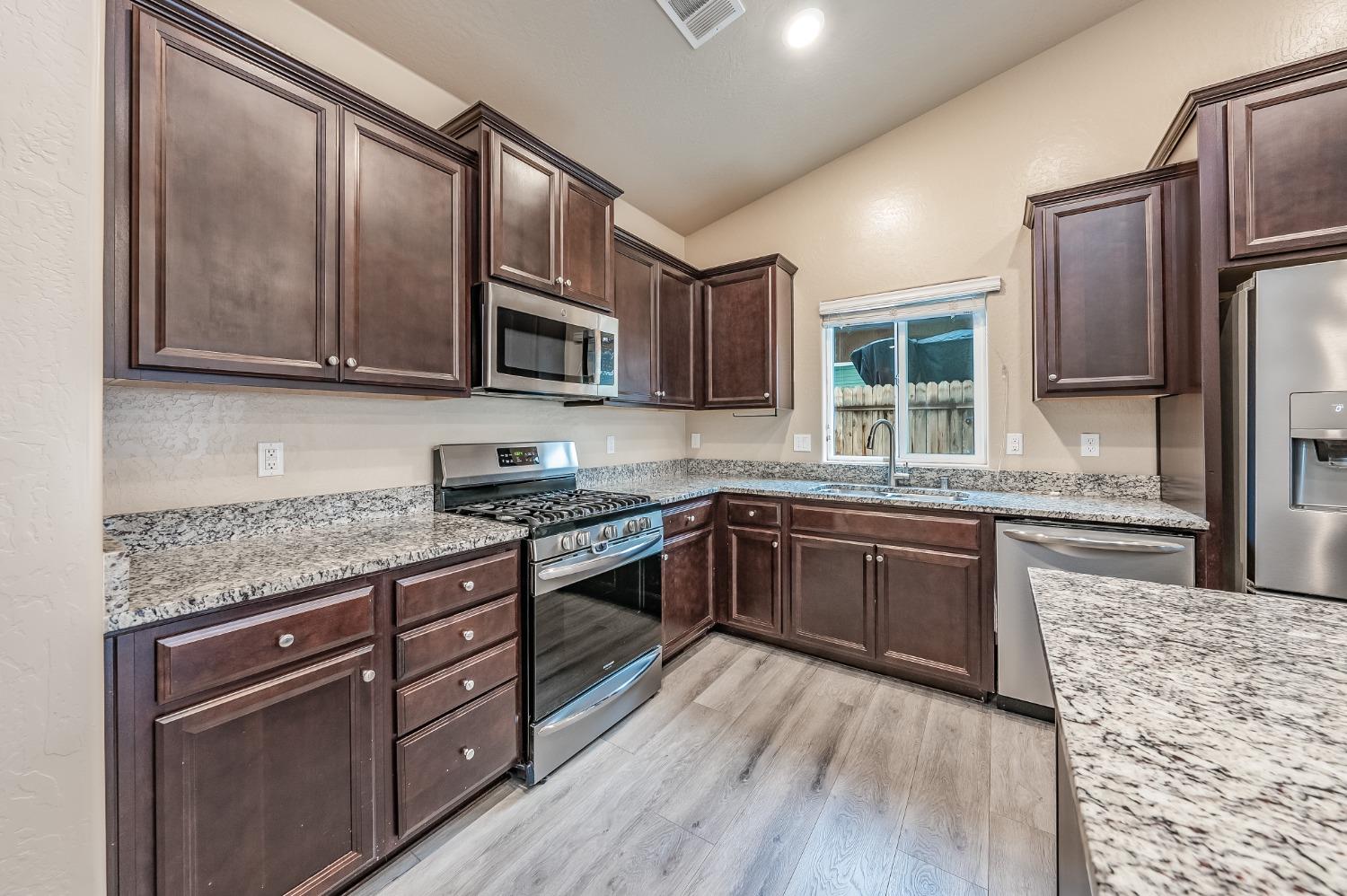 742 Strada Street Lemoore, CA 93245 - Photo 8 of 40 a kitchen with granite countertop wooden cabinets stainless steel appliances and a granite counter tops