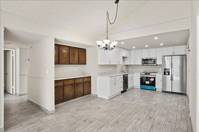 a open kitchen with stainless steel appliances granite countertop a refrigerator oven a fireplace and a sink with cabinets