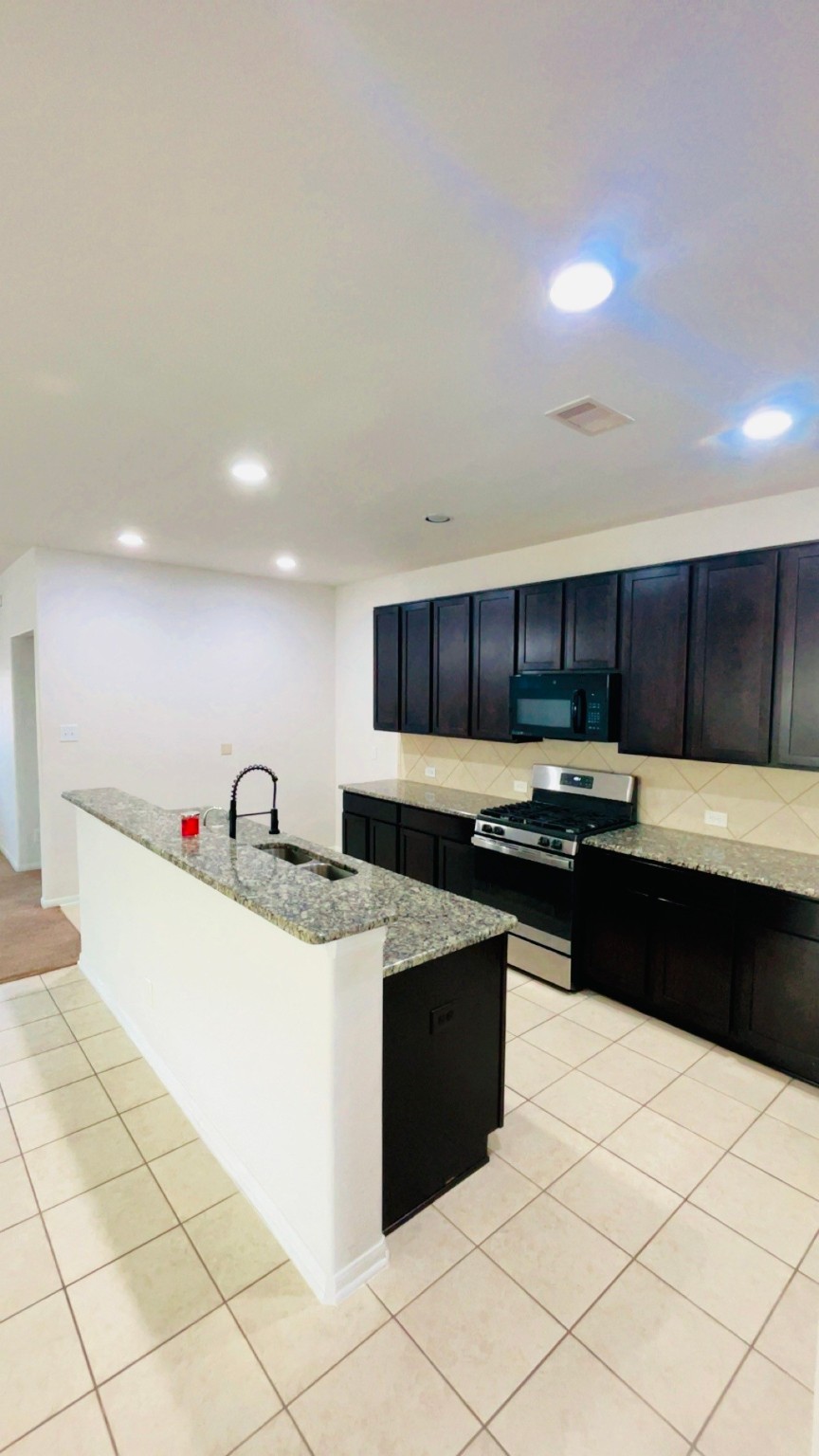 8626 Willet Street Baytown, TX 77521 - Photo 15 of 37 a kitchen with stainless steel appliances kitchen island granite countertop a sink and a stove