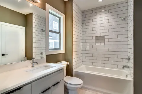 a bathroom with a bathtub shower sink vanity and toilet