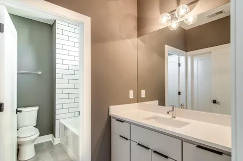 a bathroom with a sink a toilet and a large mirror