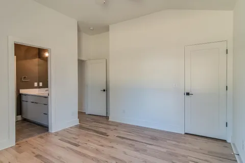 a view of an empty room with closet and wooden floor
