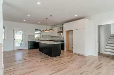 a large kitchen with stainless steel appliances kitchen island granite countertop a large counter top and wooden floors