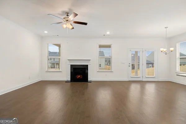 a view of an empty room with wooden floor and a fireplace