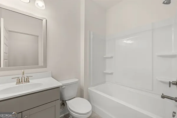 a bathroom with a bathtub shower sink vanity mirror and toilet