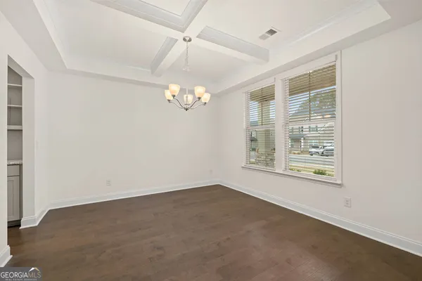 an empty room with a chandelier fan and windows