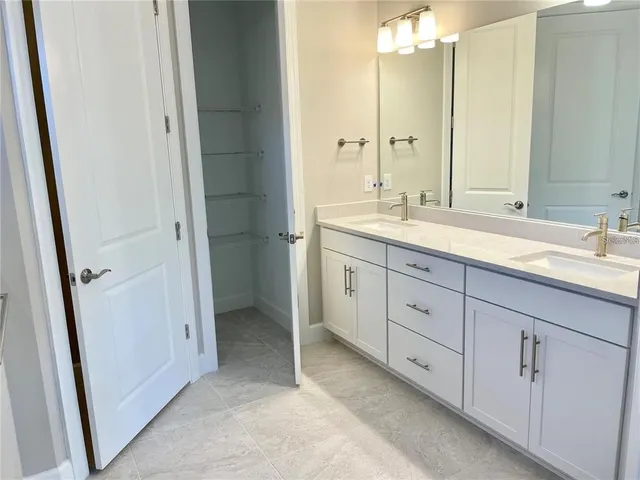 a spacious bathroom with a double vanity sink a large mirror a shower and a vanity