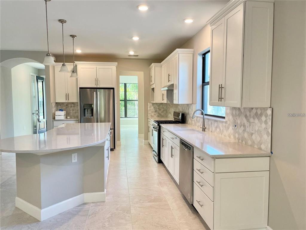 5748 Bay Pine Way Sarasota, FL 34238 - Photo 2 of 24 a kitchen with stainless steel appliances kitchen island granite countertop a refrigerator a sink and a stove