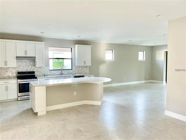 a kitchen with granite countertop a stove top oven a sink and white cabinets with wooden floor