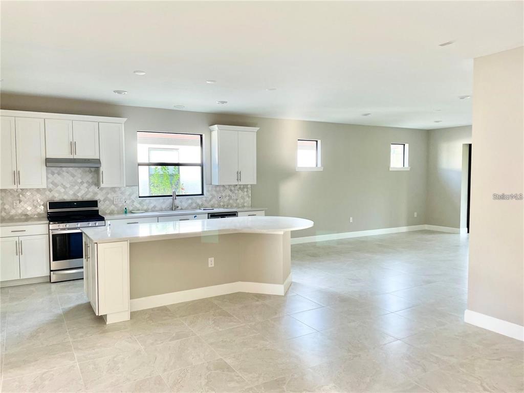 5748 Bay Pine Way Sarasota, FL 34238 - Photo 6 of 24 a kitchen with granite countertop a stove top oven a sink and white cabinets with wooden floor