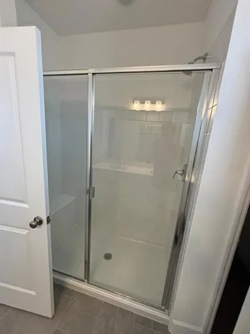 a bathroom with a glass shower door and a window