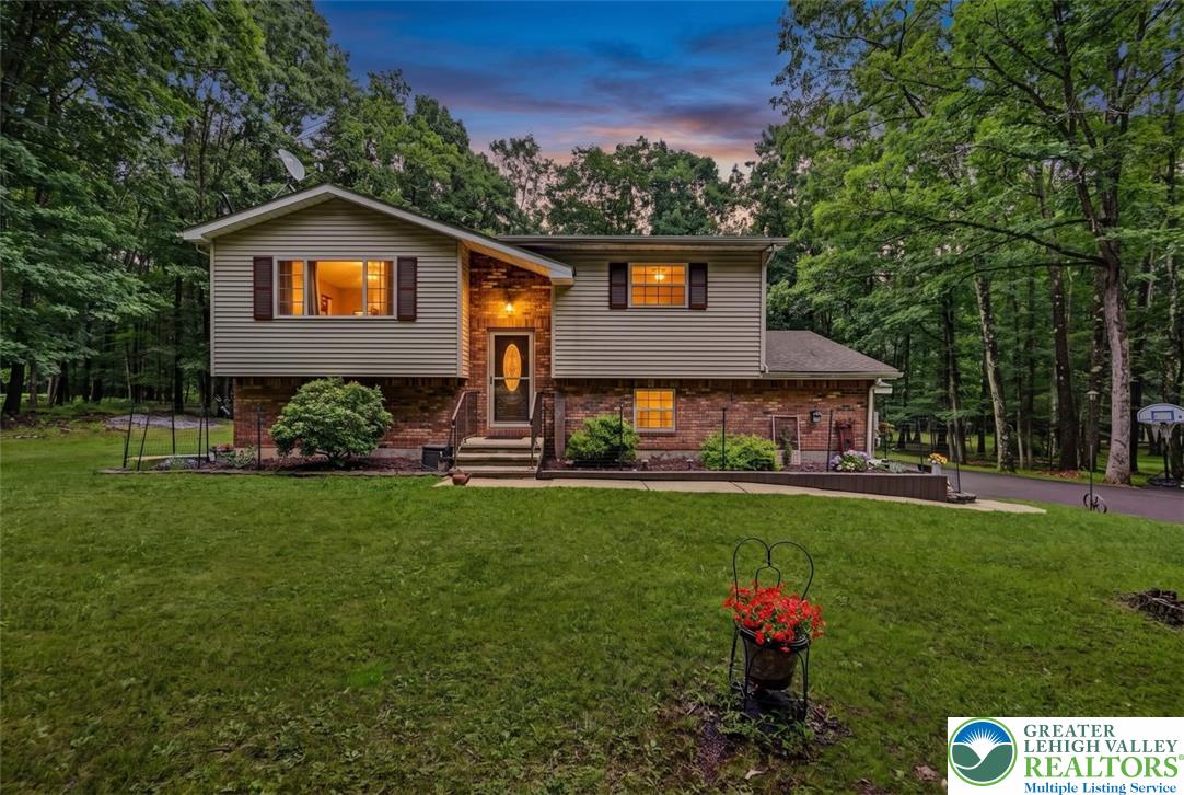 Nestled among a verdant forest, this inviting home features a charming brick and siding exterior, offering a tranquil retreat.