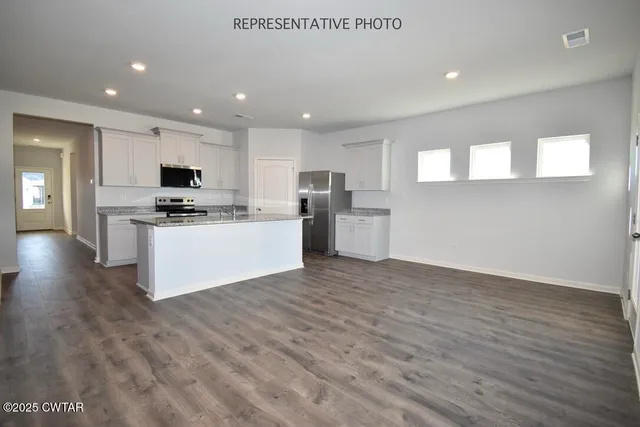 a large kitchen with stainless steel appliances granite countertop a stove a sink and a microwave