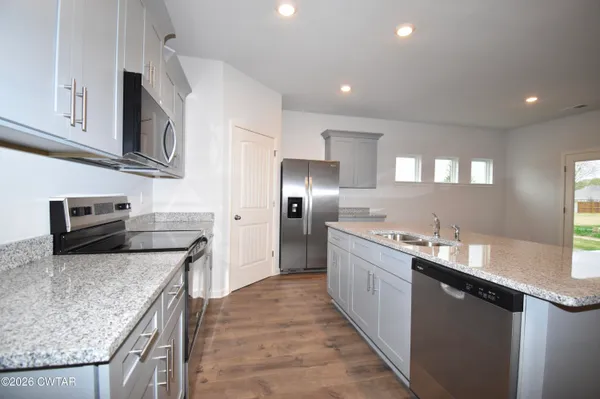 a kitchen with stainless steel appliances granite countertop a sink a stove and a refrigerator