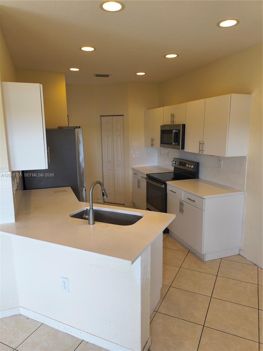 1645 Southeast 20th Road, Unit 1645 Homestead, FL 33035 - Photo 4 of 20 a kitchen with stainless steel appliances a sink stove and refrigerator