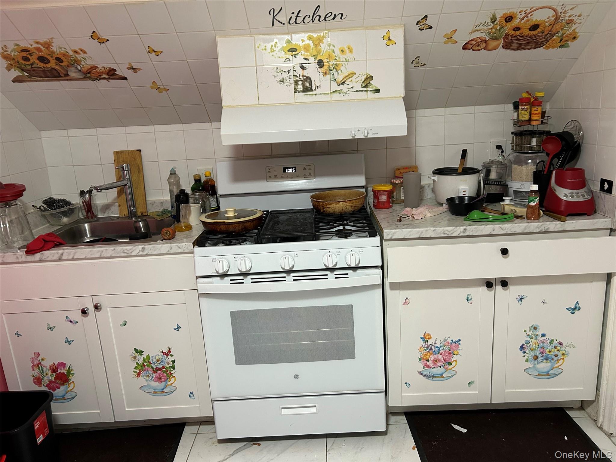 11 Sherman Street, Unit 2 Spring Valley, NY 10977 - Photo 4 of 5 a kitchen with a stove a refrigerator and white cabinets