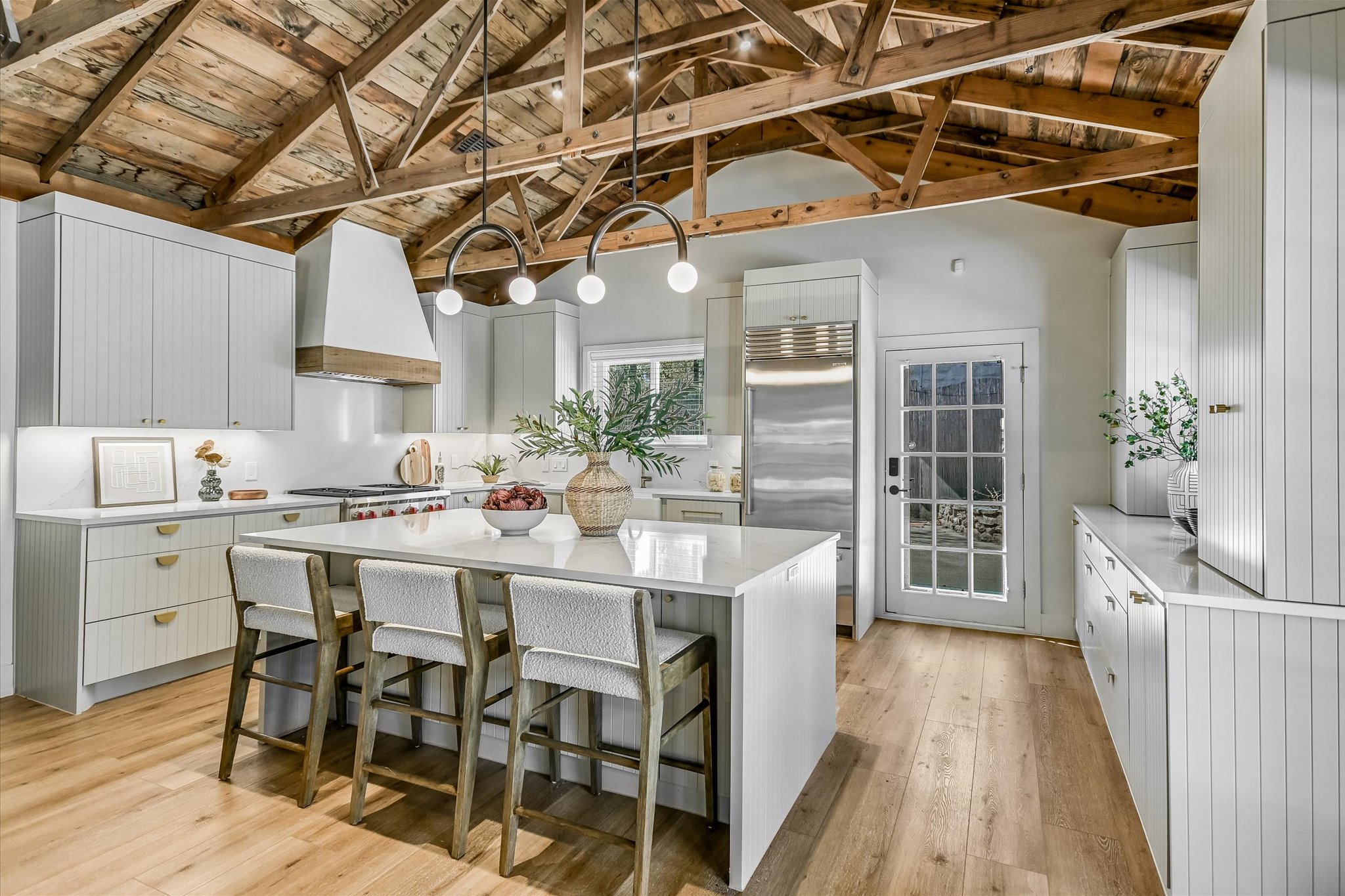 Kitchen featuring a high wood beamed ceiling, a kitchen breakfast bar, built in refrigerator, a kitchen island, and light wood-style flooring