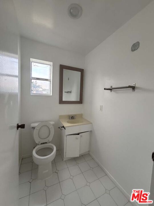 915 Broadway Street, Unit 2 Venice, CA 90291 - Photo 17 of 31 a bathroom with a granite countertop toilet a sink and a mirror