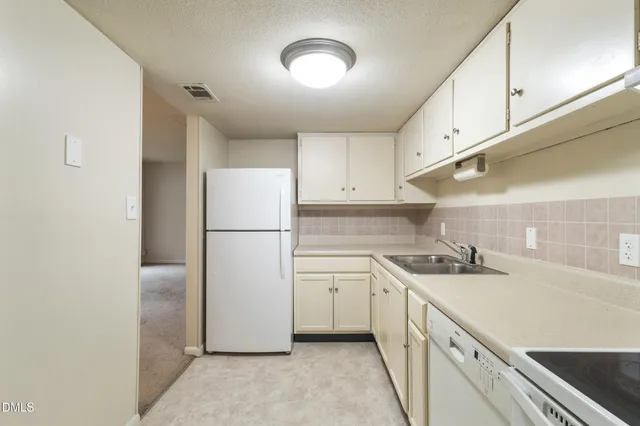 a kitchen with a sink a refrigerator and cabinets