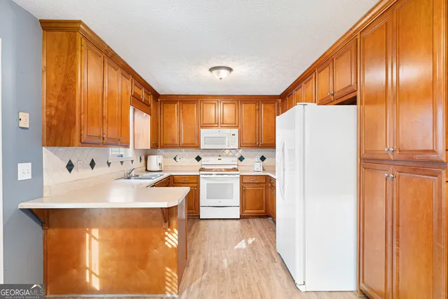 a large kitchen with stainless steel appliances granite countertop a refrigerator a sink dishwasher a dining table and chairs with wooden floor
