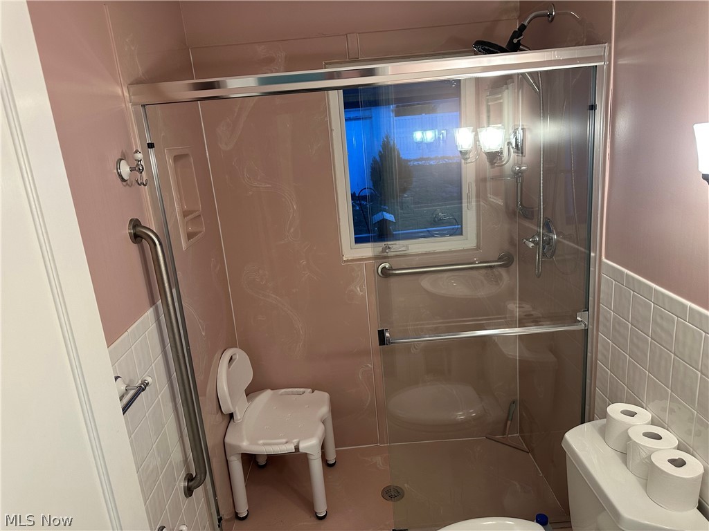 3192 Mogadore Road Akron, OH 44312 - Photo 22 of 43 First Floor Full bath featuring tile walls, a wainscoted wall, and a stall shower