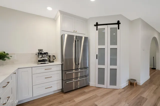 a kitchen with granite countertop a refrigerator cabinets and wooden floor