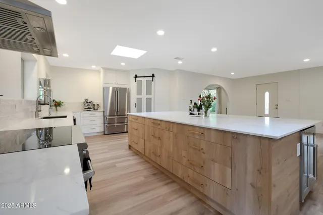 a large kitchen with kitchen island a counter top space a sink and stainless steel appliances