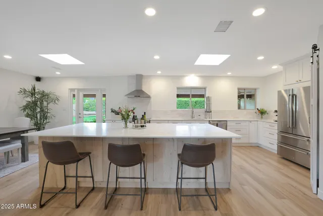 a kitchen with stainless steel appliances kitchen island granite countertop a dining table chairs and refrigerator