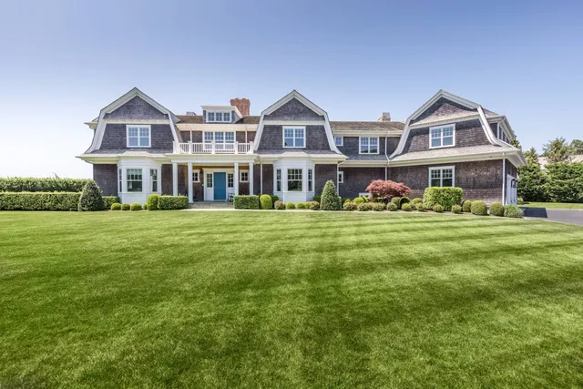 a front view of a house with garden and trees