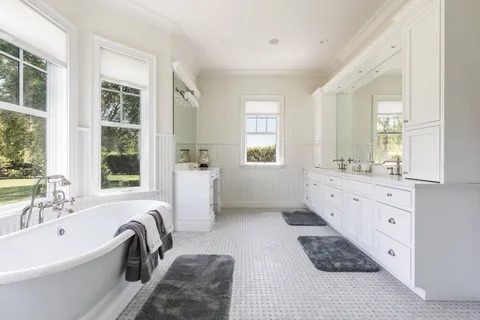 a bathroom with a tub sink a window and mirror