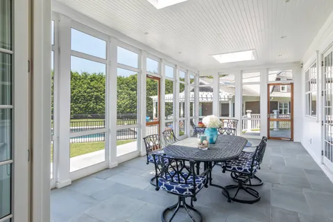 a dining room with furniture large windows and a chandelier