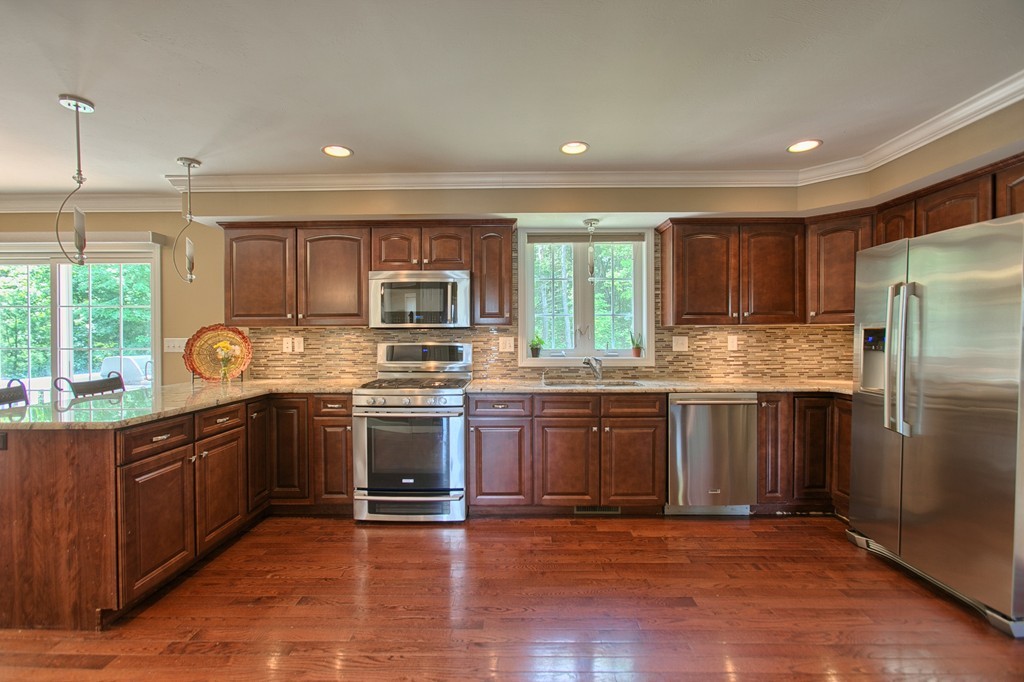 72 Clement Road Dracut, MA 01826 - Photo 13 of 30 a kitchen with stainless steel appliances granite countertop a refrigerator a stove top oven a sink and dishwasher with wooden floor