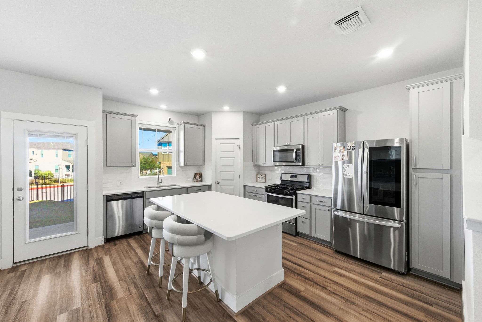 7416 Travertine Spring Drive, Unit 149 Austin, TX 78744 - Photo 12 of 36 a large kitchen with a center island wooden floor stainless steel appliances and cabinets