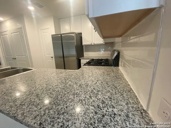 a view of a refrigerator in kitchen and an empty room