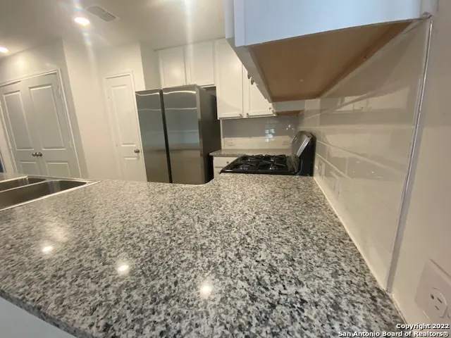 a view of a refrigerator in kitchen and an empty room