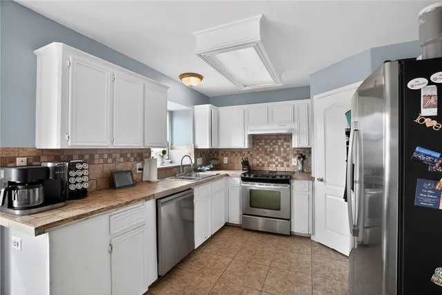a kitchen with a sink white cabinets and stainless steel appliances