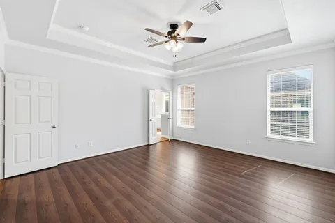 an empty room with wooden floor chandelier fan and windows