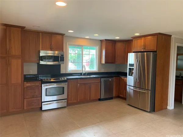 a kitchen with stainless steel appliances granite countertop a refrigerator a stove a sink and a microwave