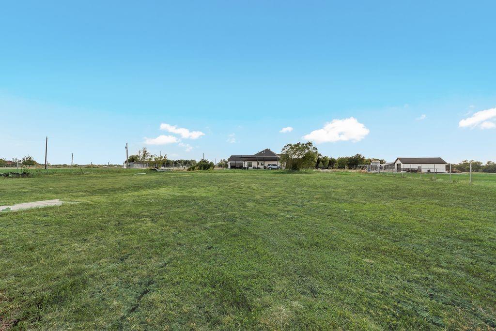 610 Ewing Road Ferris, TX 75125 - Photo 22 of 22 Expansive green space featuring a residence with a dark roof and a separate outbuilding with a dark roof
