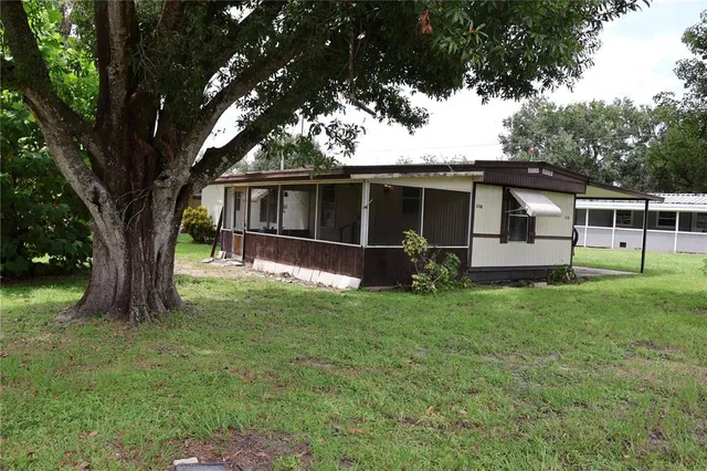 a view of a house with backyard and a tree