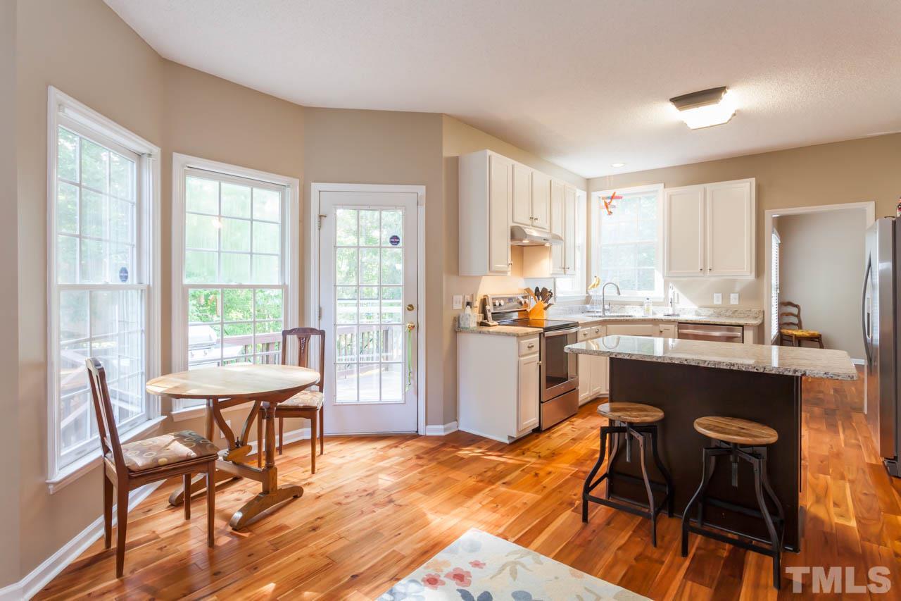 12308 Hartwick Court Raleigh, NC 27613 - Photo 5 of 20 a kitchen with stainless steel appliances kitchen island granite countertop wooden floor dining table and chairs