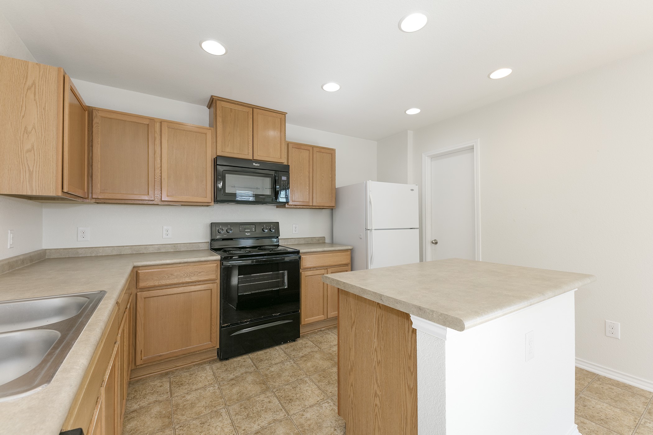 1141 Renaissance Trail Round Rock, TX 78665 - Photo 4 of 23 A well-lit kitchen with natural wood cabinetry and resilient tile flooring for easy maintenance.